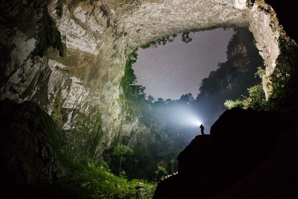A caver looks out at stars through the second doline in Hang Son Doong, Phong Nha Ke Bang, Vietnam