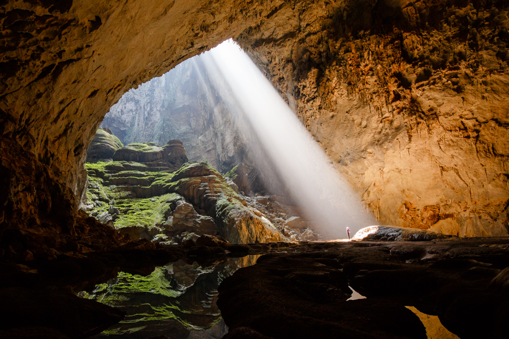 A caver stands in a sunbeam coming through the first doline in Hang Son Doong, Phong Nha Ke Bang, Vietnam