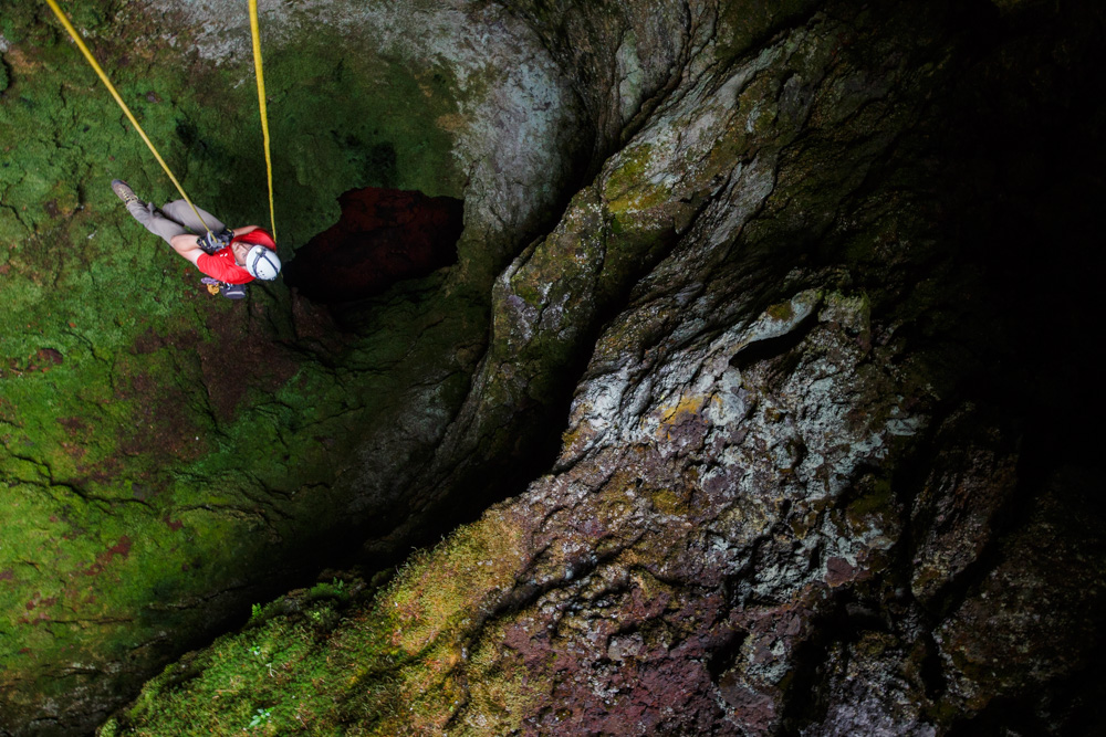 A caver ascends out of a lava tube in Oregon.
