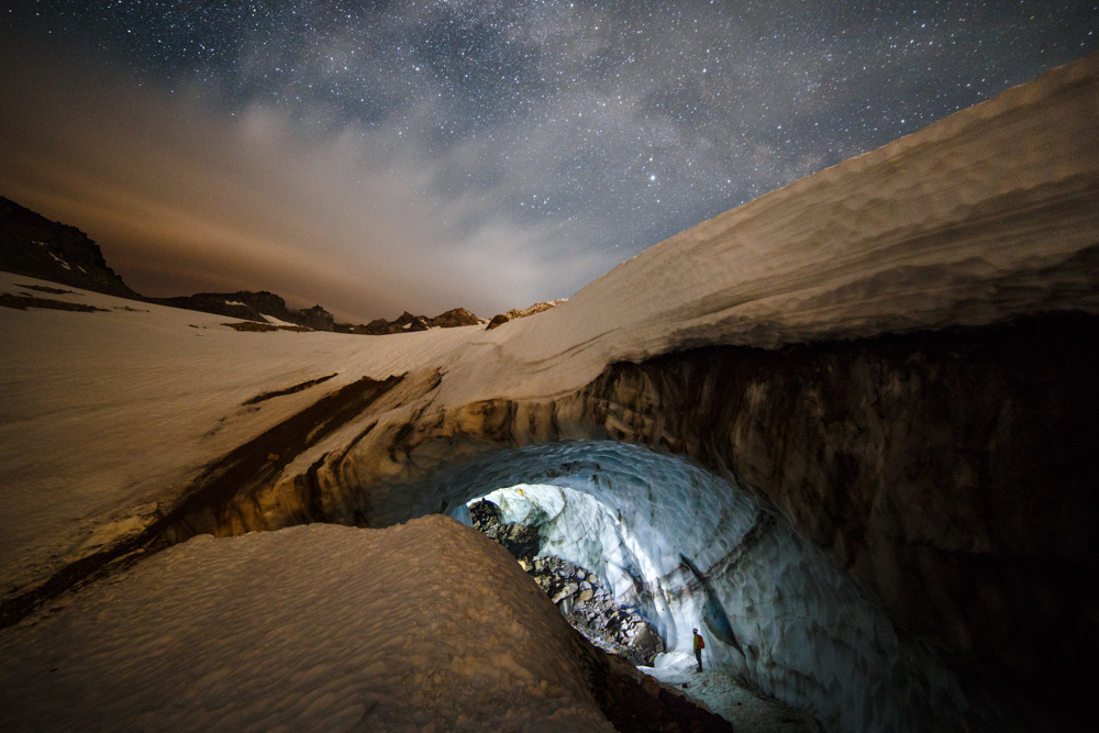 Entering a glacier cave on Mt Hood under a starry night.